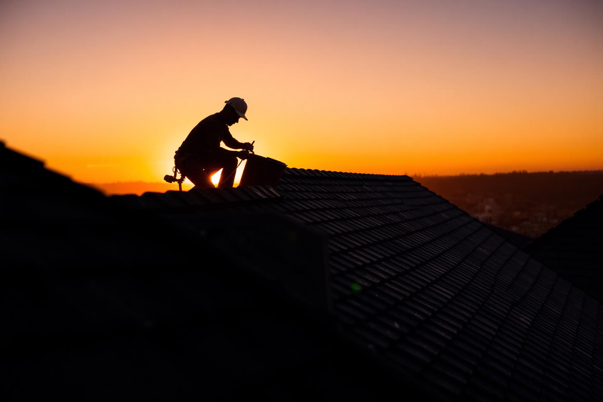 Dachdecker bei Sonnenuntergang auf einem deutschen Ziegeldach